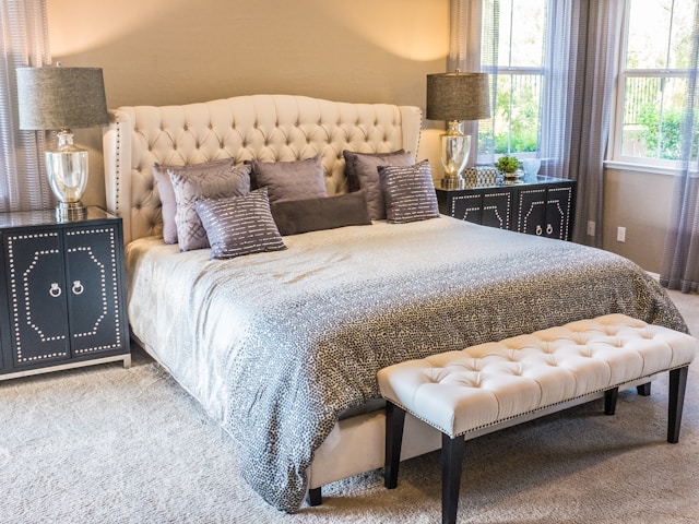 A softly lit bedroom with a tufted headboard and layered linens