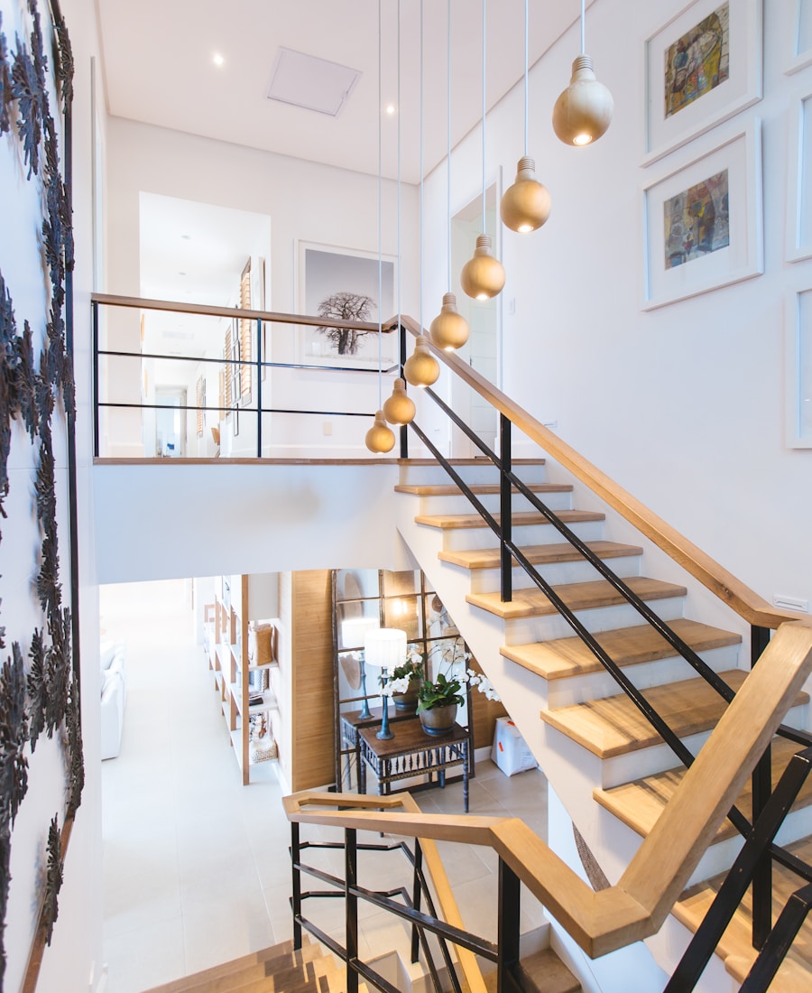 A bright entry hall with an open wooden staircase and pendant lights
