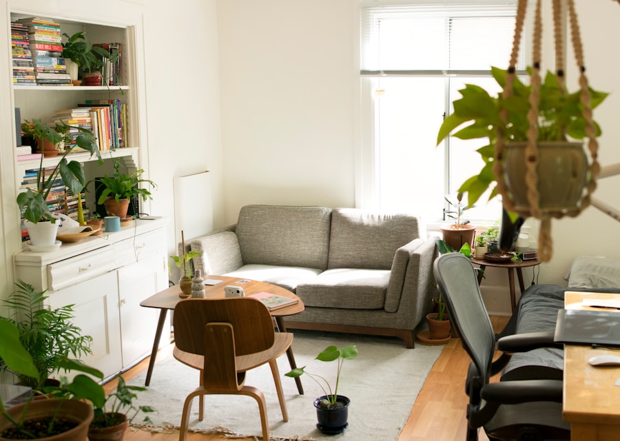 A bright, plant-filled living room with a grey sofa and warm wood floors