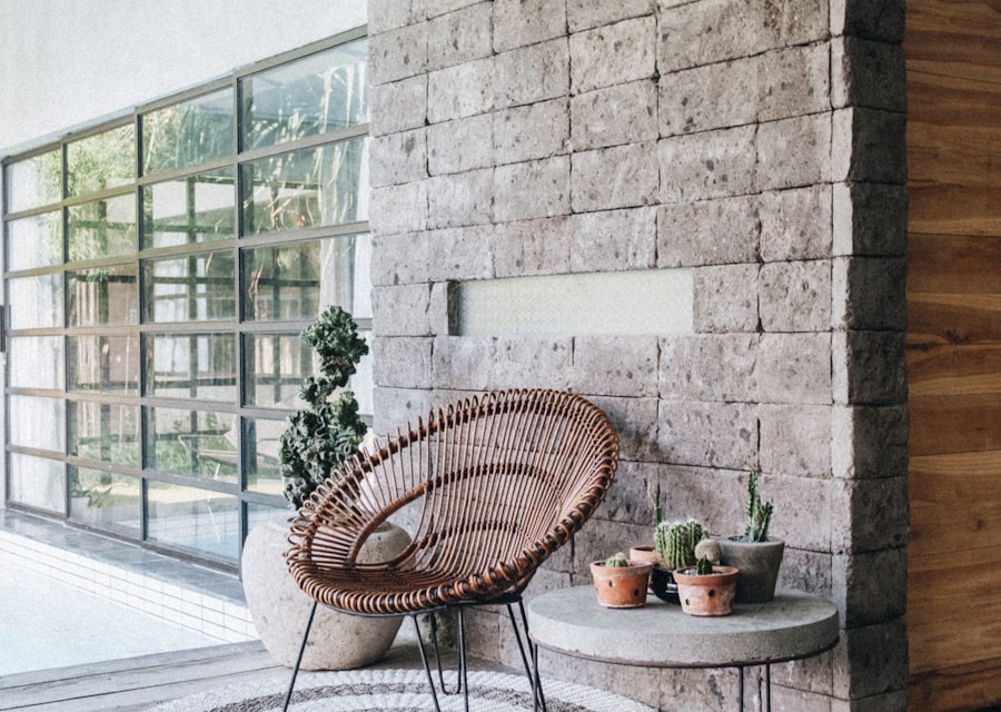 A woven chair beside a stone wall and tall windows