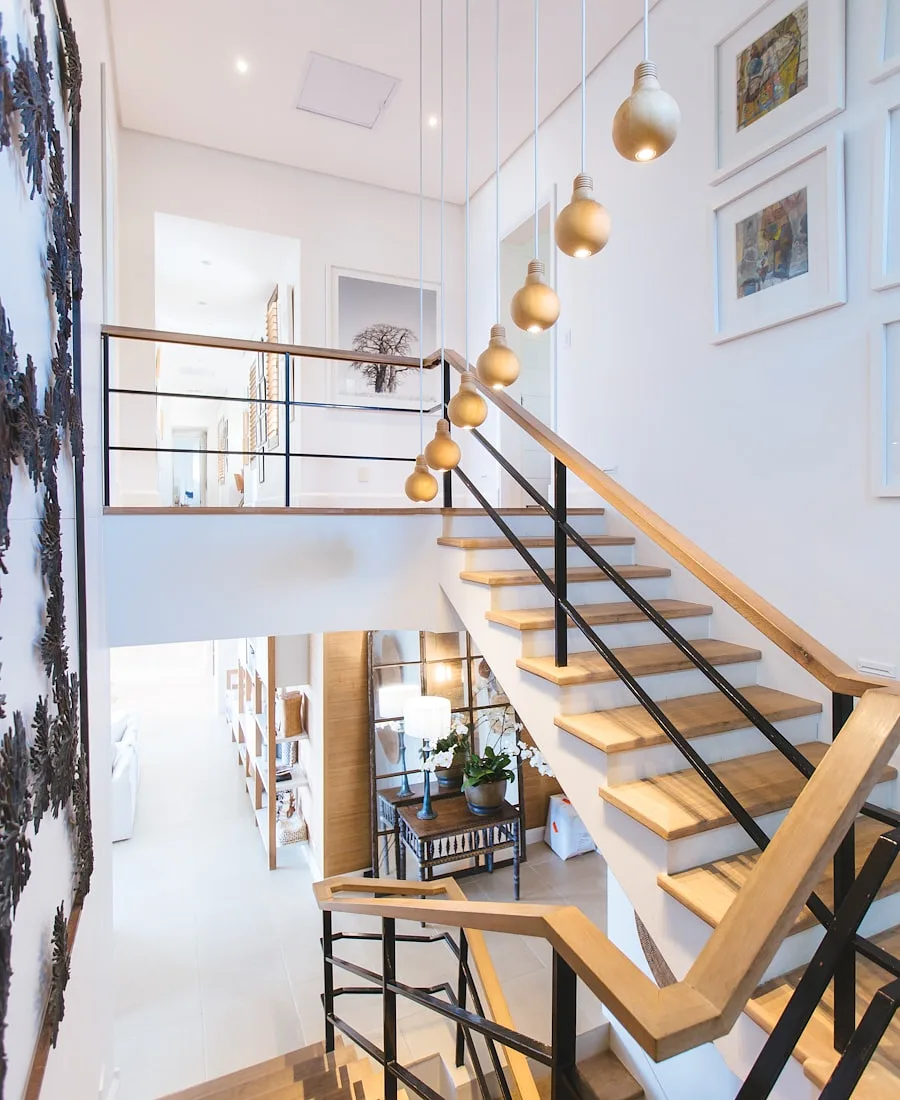 A bright entry hall with an open wooden staircase and pendant lights