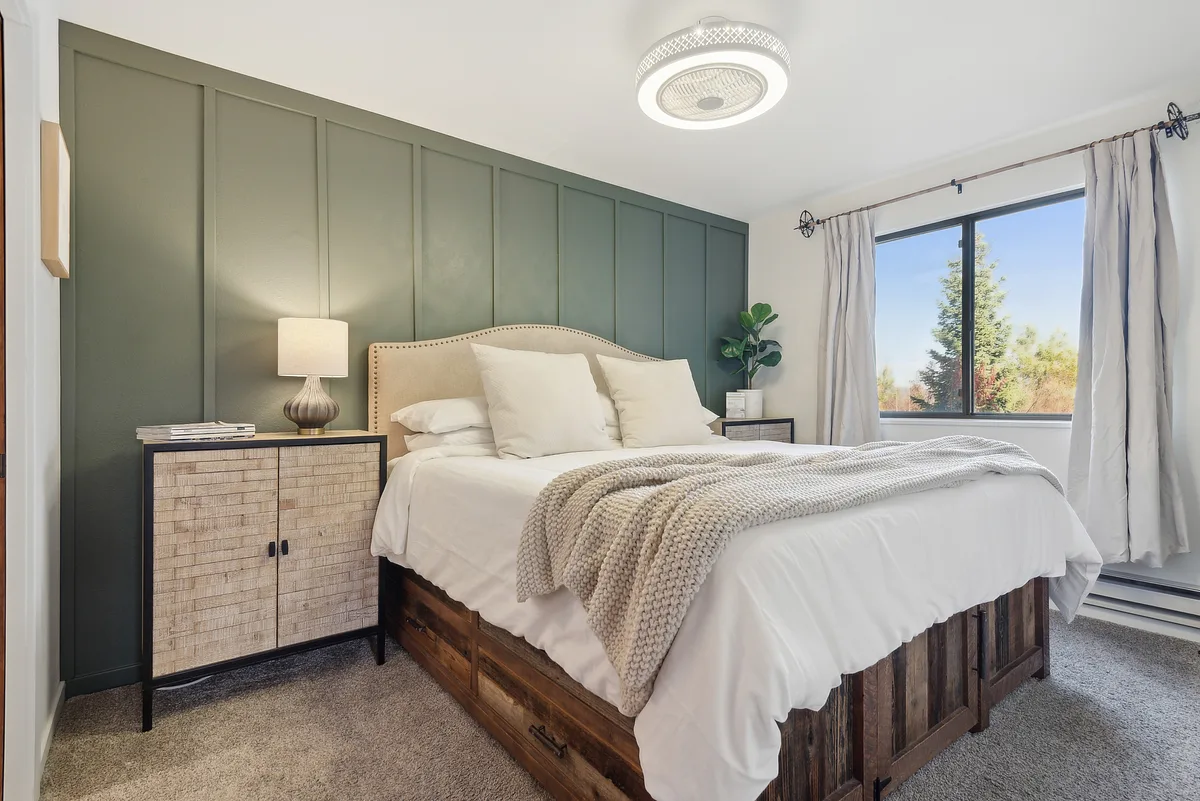 A softly lit bedroom with a tufted headboard and layered linens